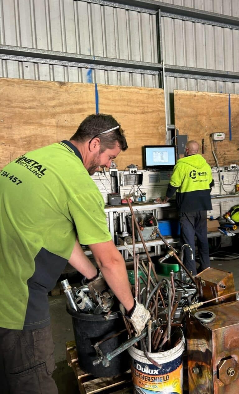 A Man in A Green Shirt Is Working in A Warehouse — H & H Metal Recycling In Coolum, QLD