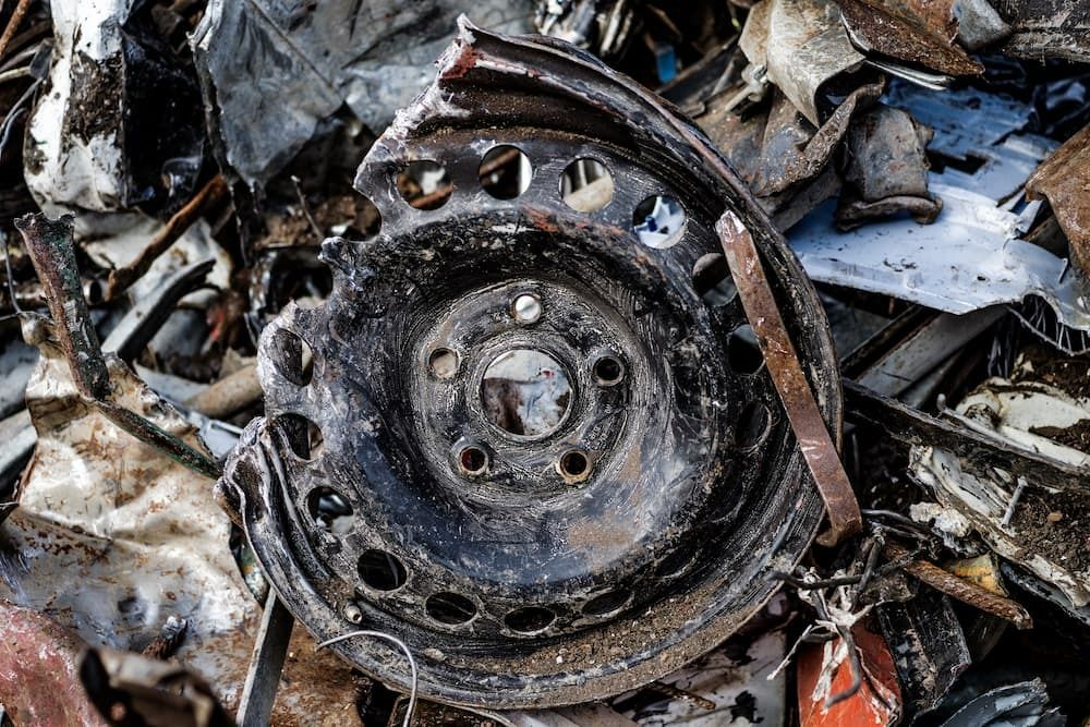 A Close up Of a Rusty Wheel in A Pile of Scrap Metal — H & H Metal Recycling In Coolum, QLD