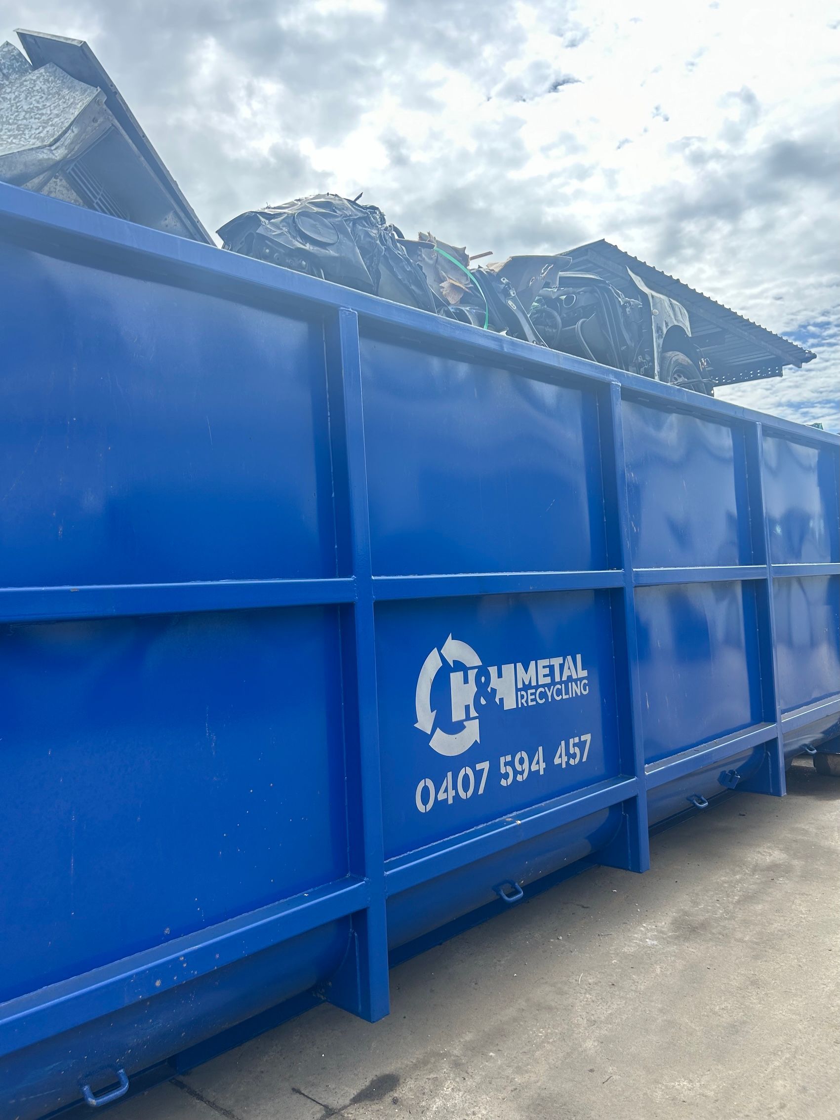 A Blue Dumpster Filled with Scrap Metal — H & H Metal Recycling In Coolum, QLD