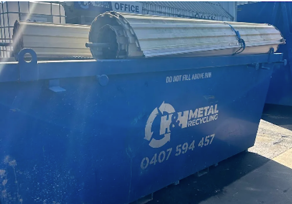 A H&H skip bin overloaded with old roller doors destined for recycling.