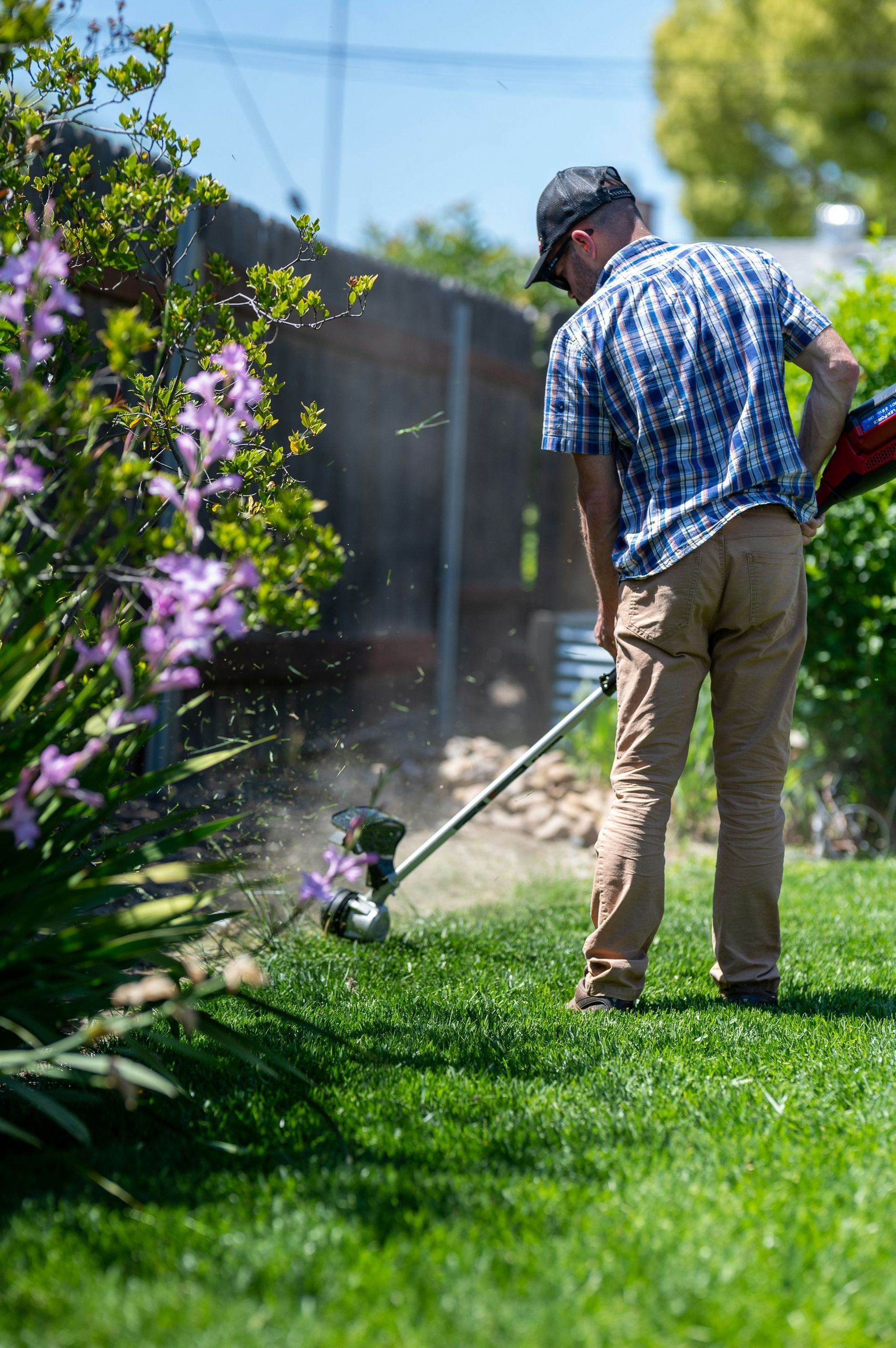 man in blue shirt snipping grass