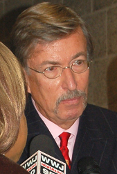 A child and a uniformed police officer stand in front of a police station with glass doors.