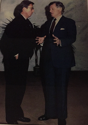 A child and a uniformed police officer stand in front of a police station with glass doors.