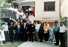 A child and a uniformed police officer stand in front of a police station with glass doors.