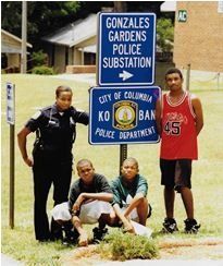 A child and a uniformed police officer stand in front of a police station with glass doors.