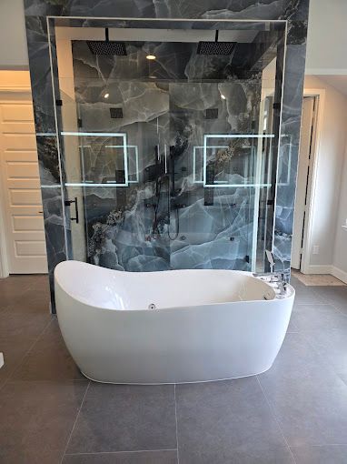 Modern bathroom with freestanding white tub in front of a black marble glass shower enclosure