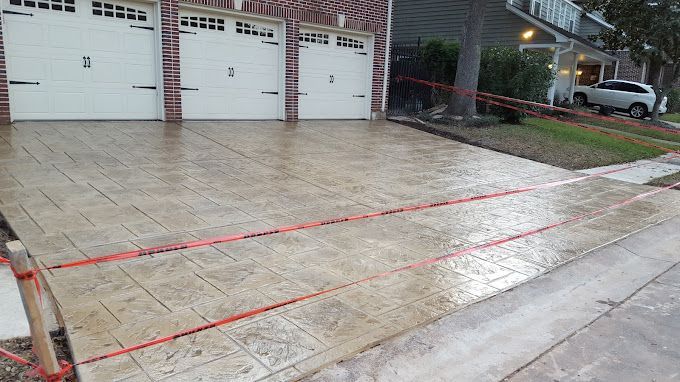 Wet concrete driveway and sidewalk in front of white garage doors on a residential street.