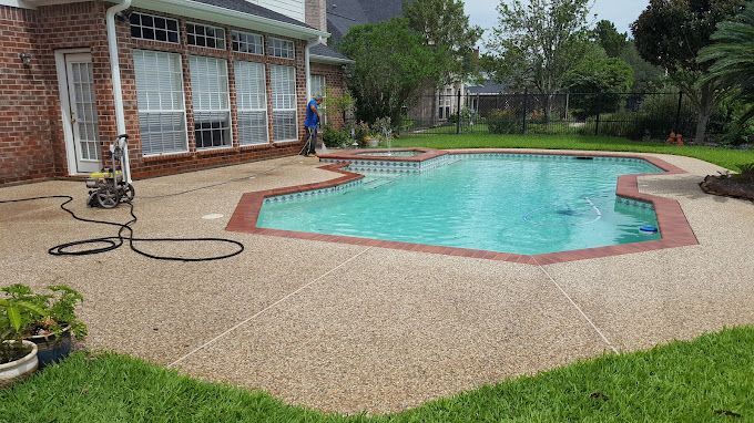 Backyard patio with a turquoise swimming pool beside a brick house and green lawn