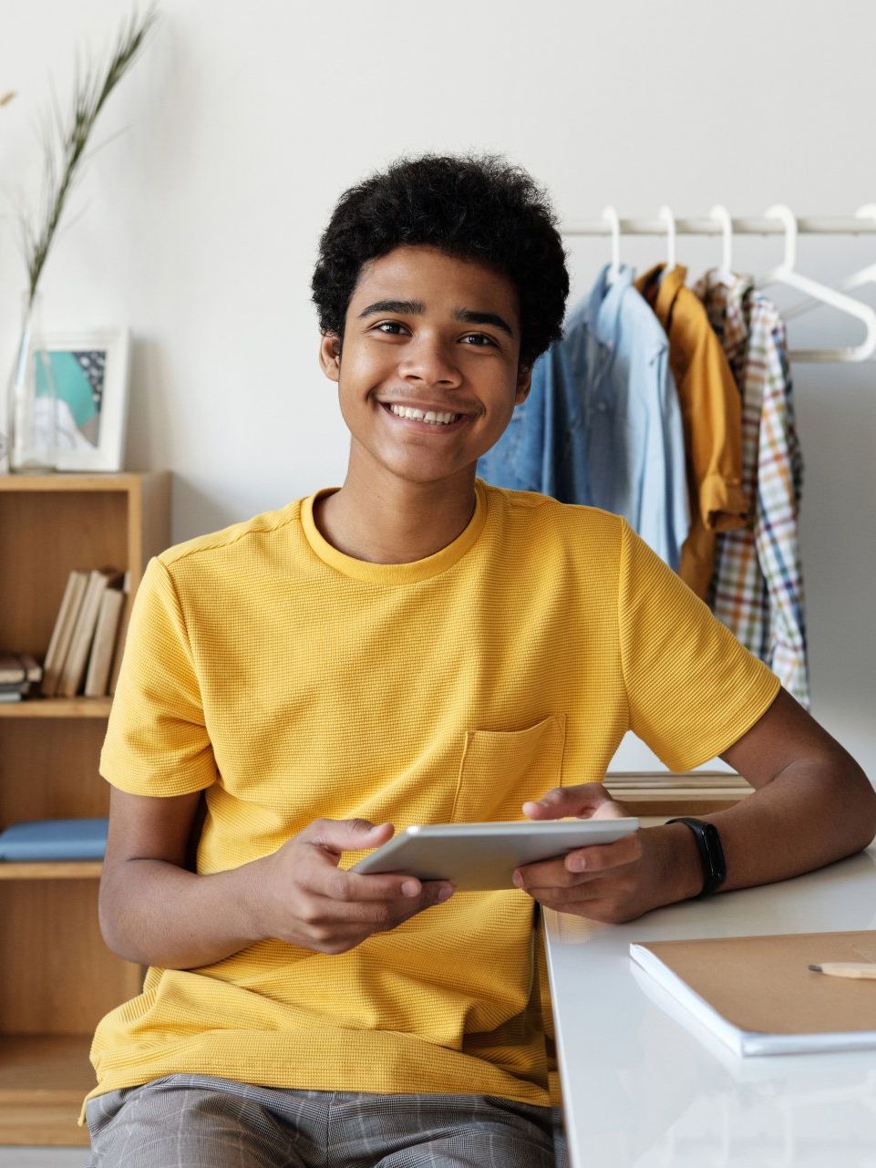 teen using a tablet device wearing a yellow shirt