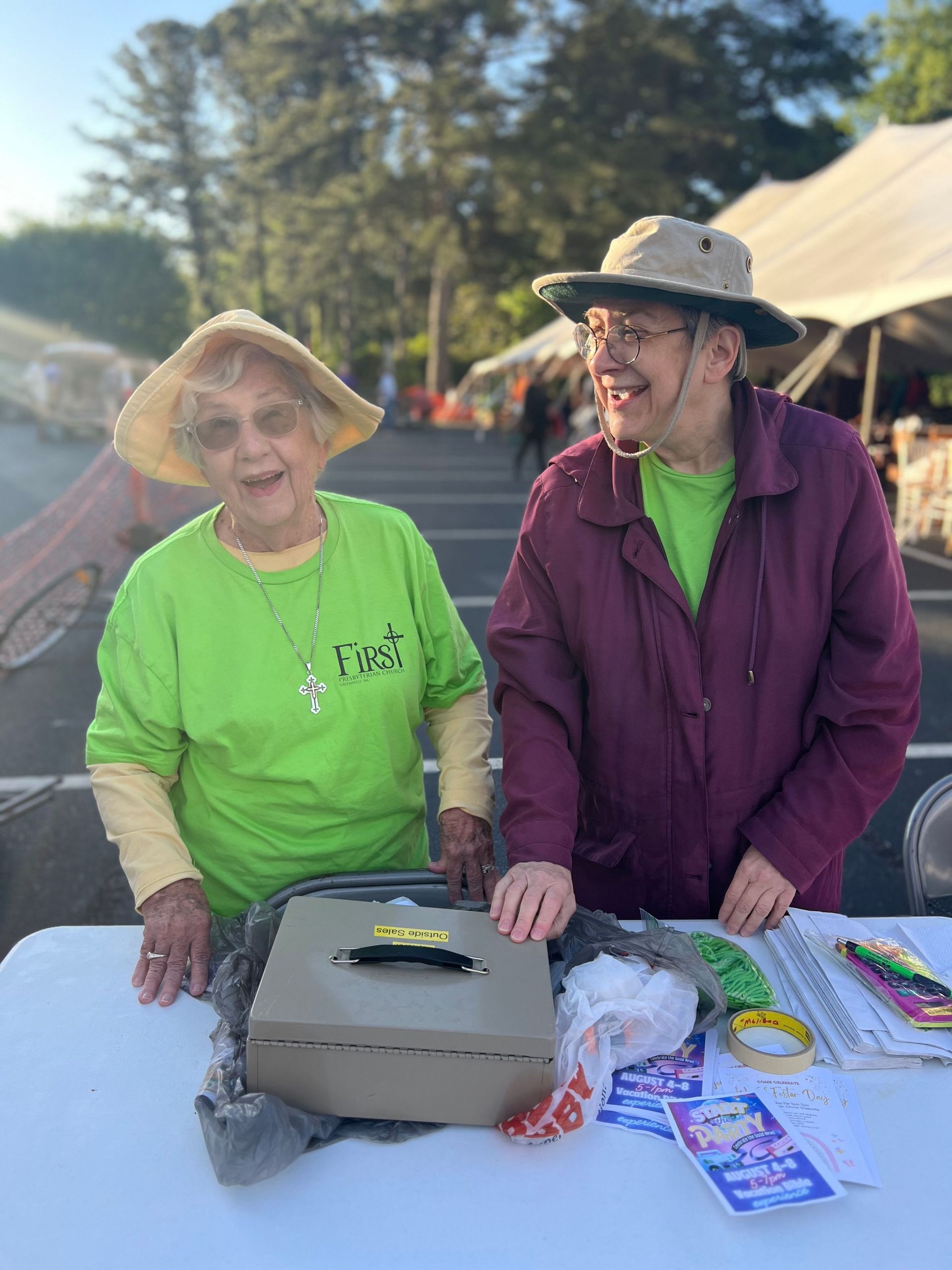 Two older women are standing next to each other at a table.