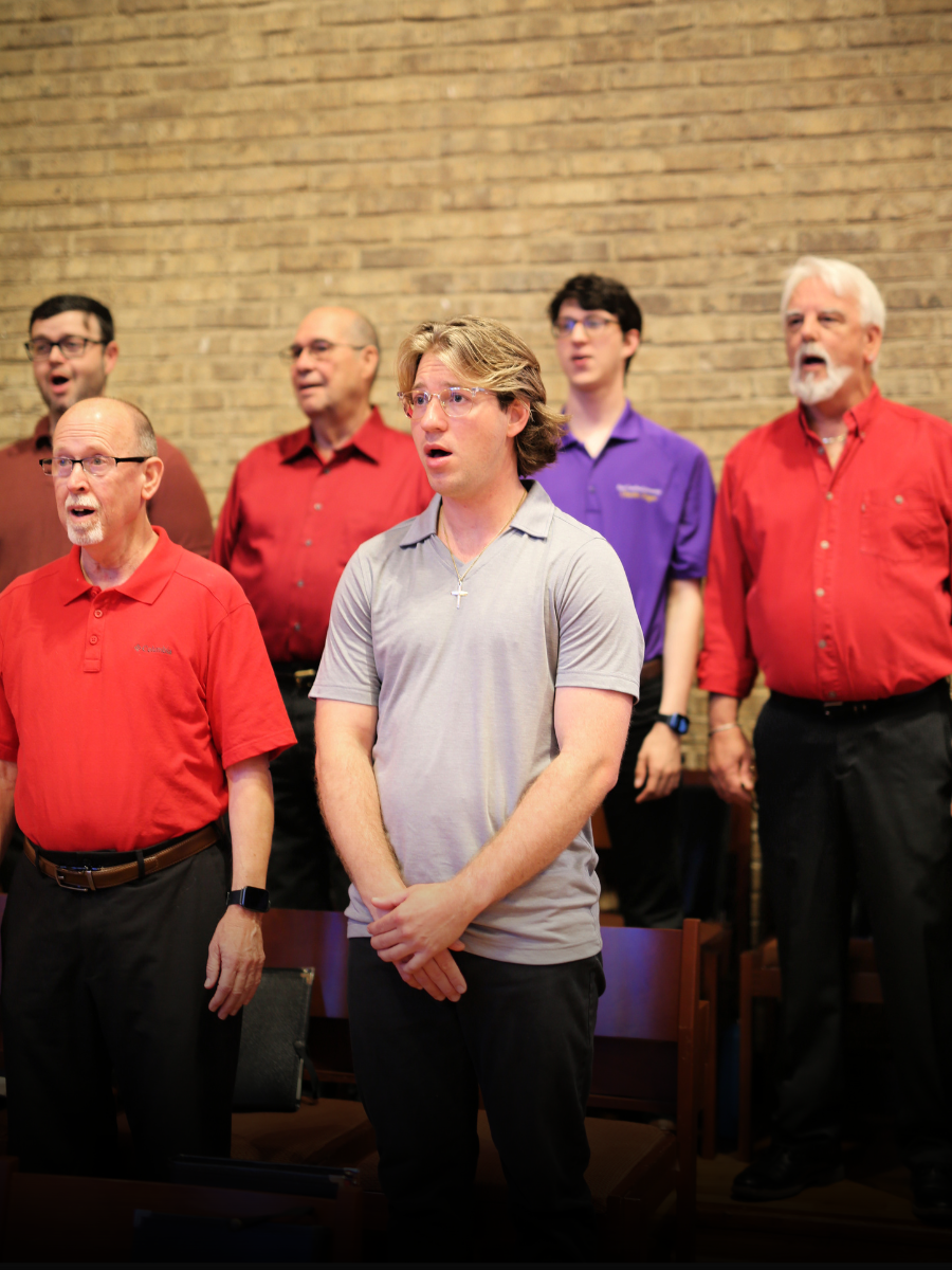 A group of men singing in front of a brick wall
