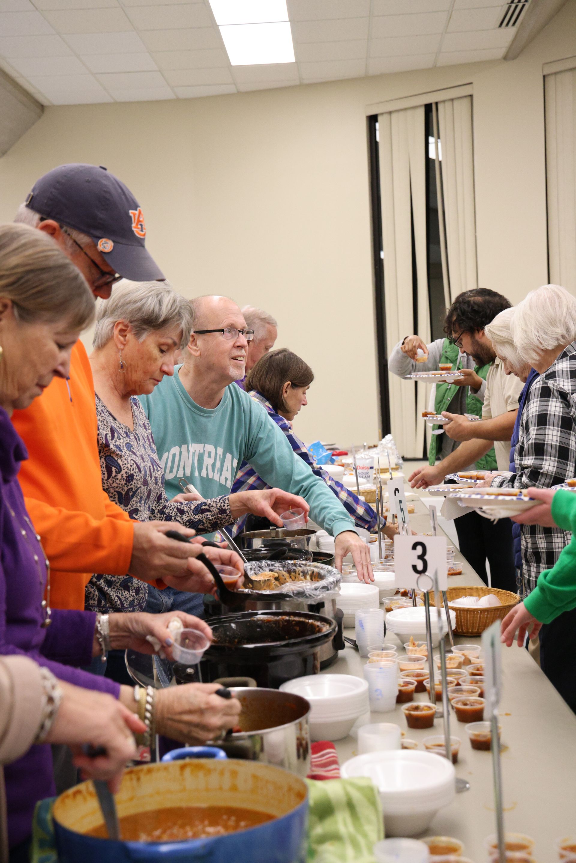 A group of people are standing around a table eating food.