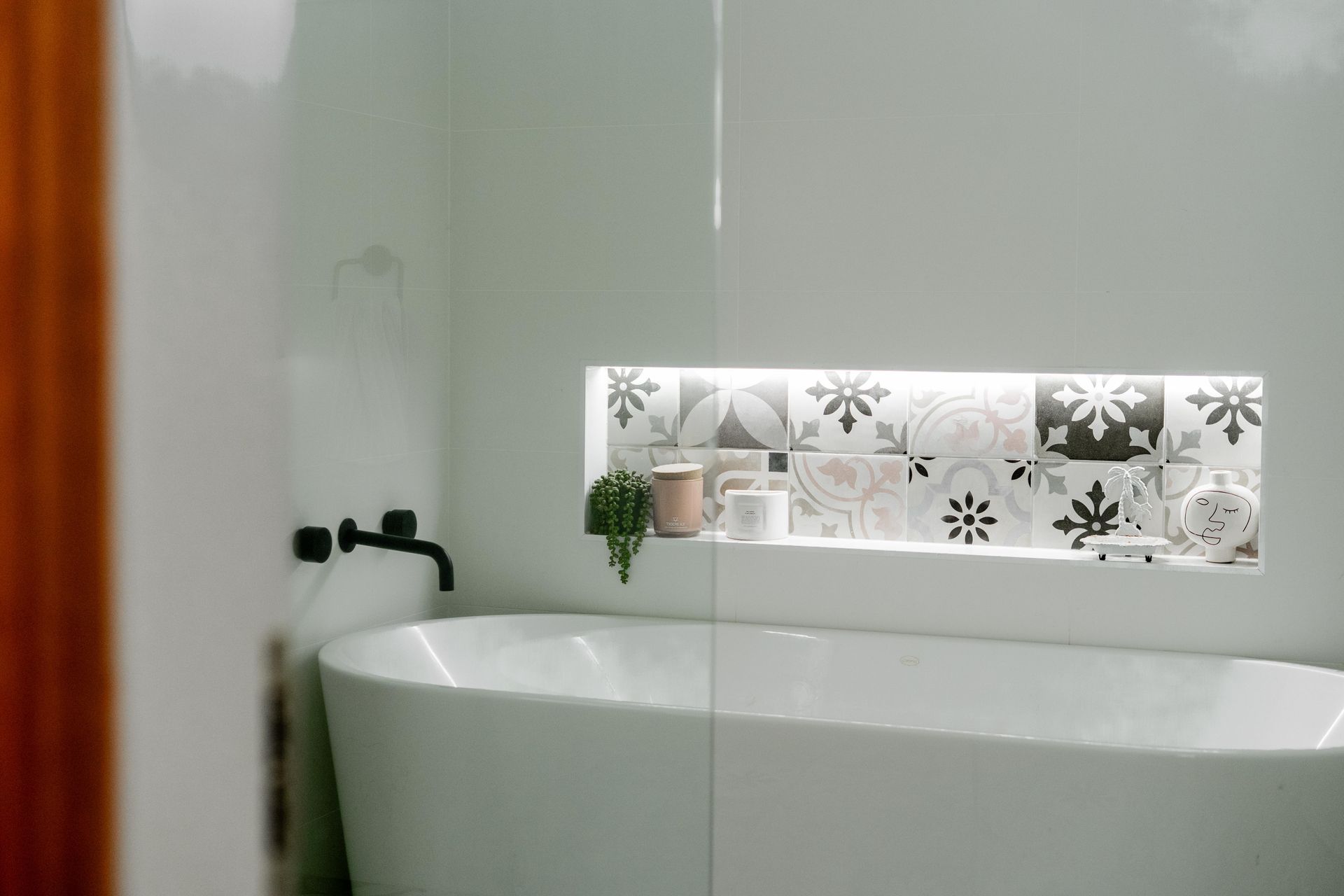 Minimalist bathroom with a white freestanding tub and frosted floral window panel — Cobra Plumbing & Bathrooms in Kiama, NSW