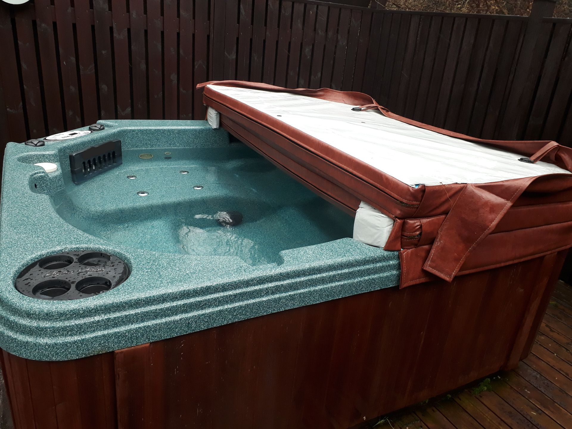 A hot tub with a red cover is sitting on a wooden deck.