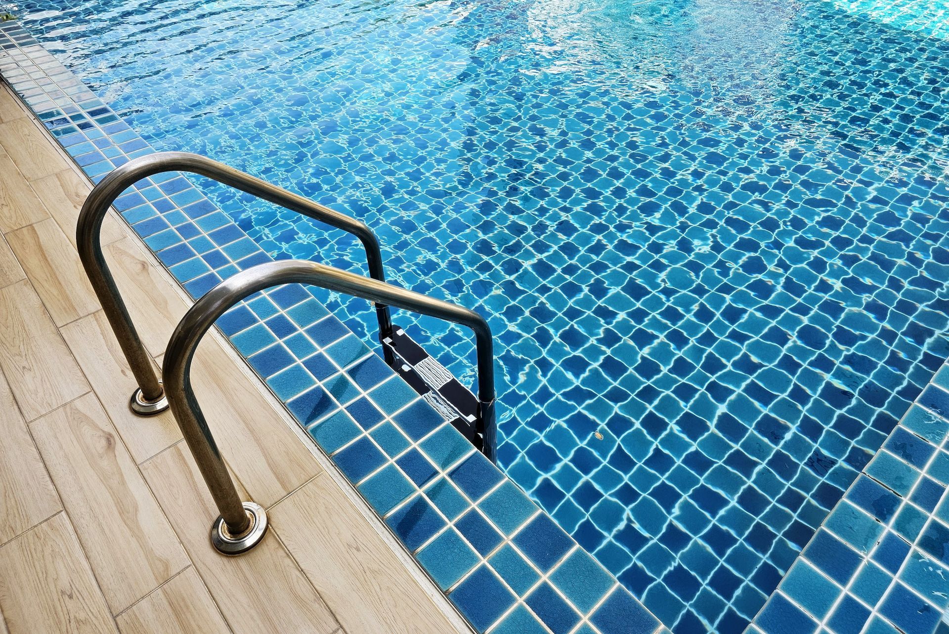 A staircase leading to a swimming pool with blue tiles.