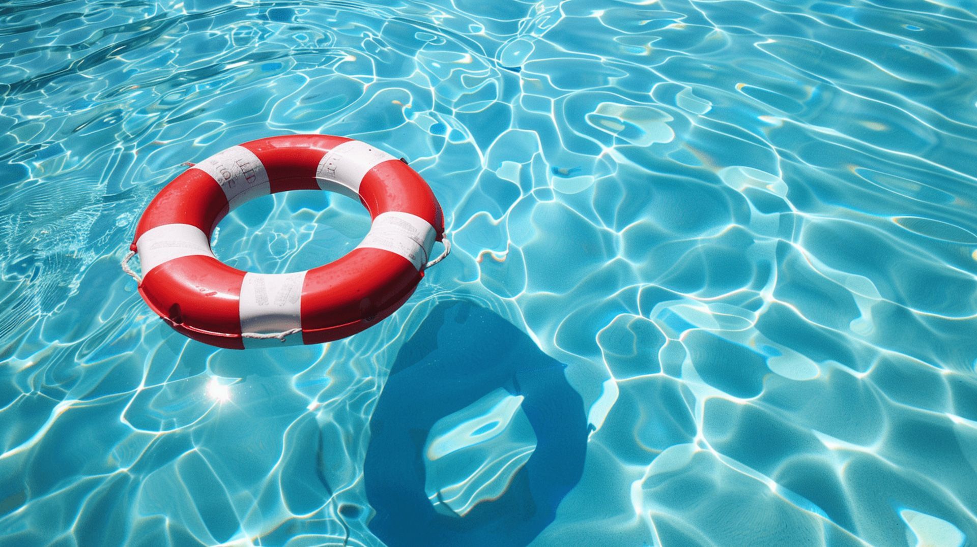 A red and white life preserver is floating in a swimming pool.