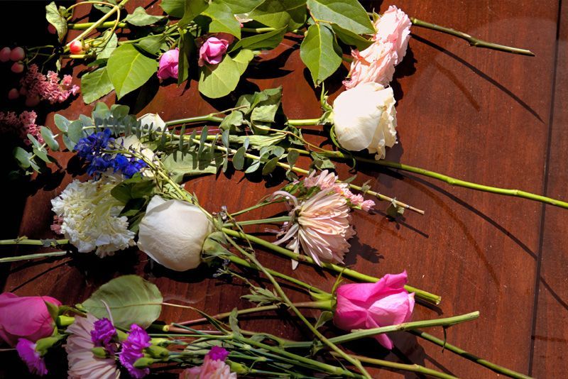 A collection of colorful roses, hydrangeas, and greenery scattered across a dark wooden surface.