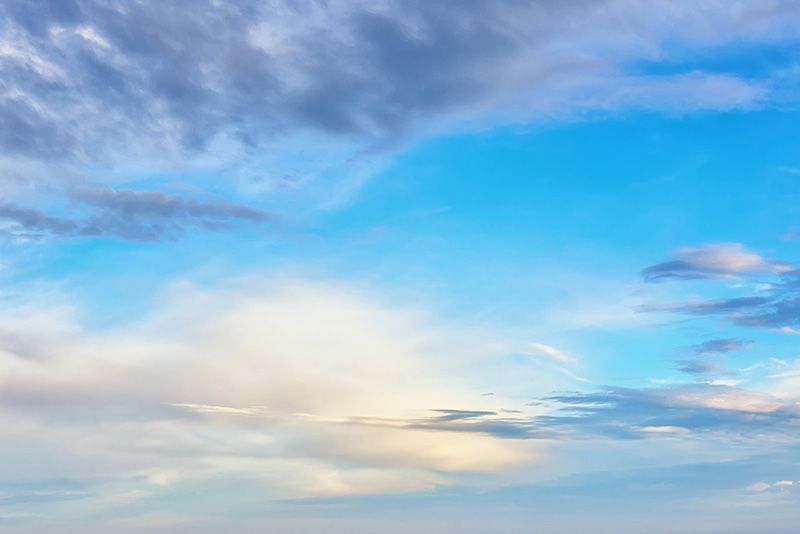 A blue sky with a mix of wispy white clouds and patches of darker, gray-toned clouds scattered across the scene.