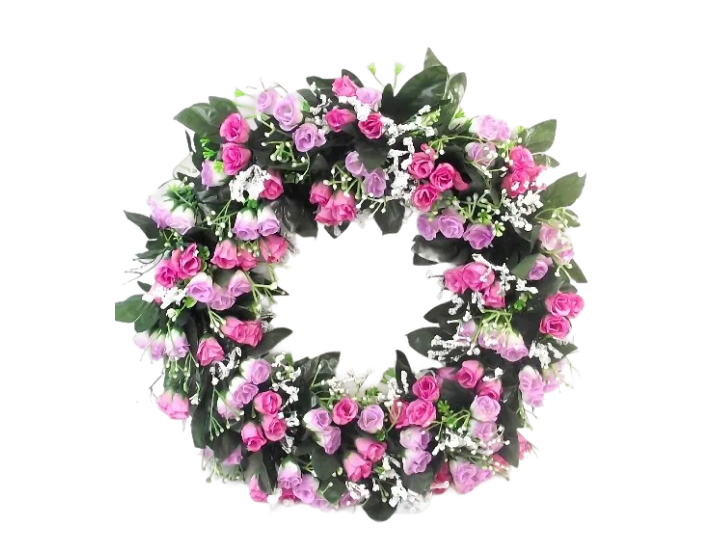 A decorative wreath made of many small pink and purple artificial roses and green leaves against a white background.