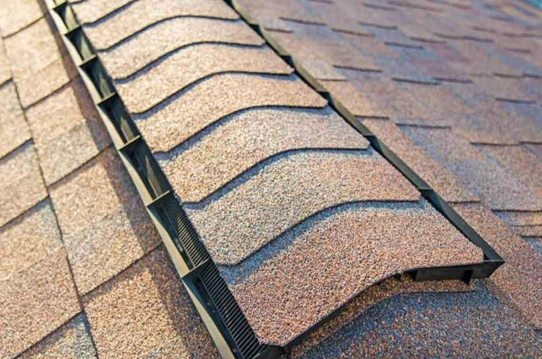 A close up of a roof with shingles and a drain on it.
