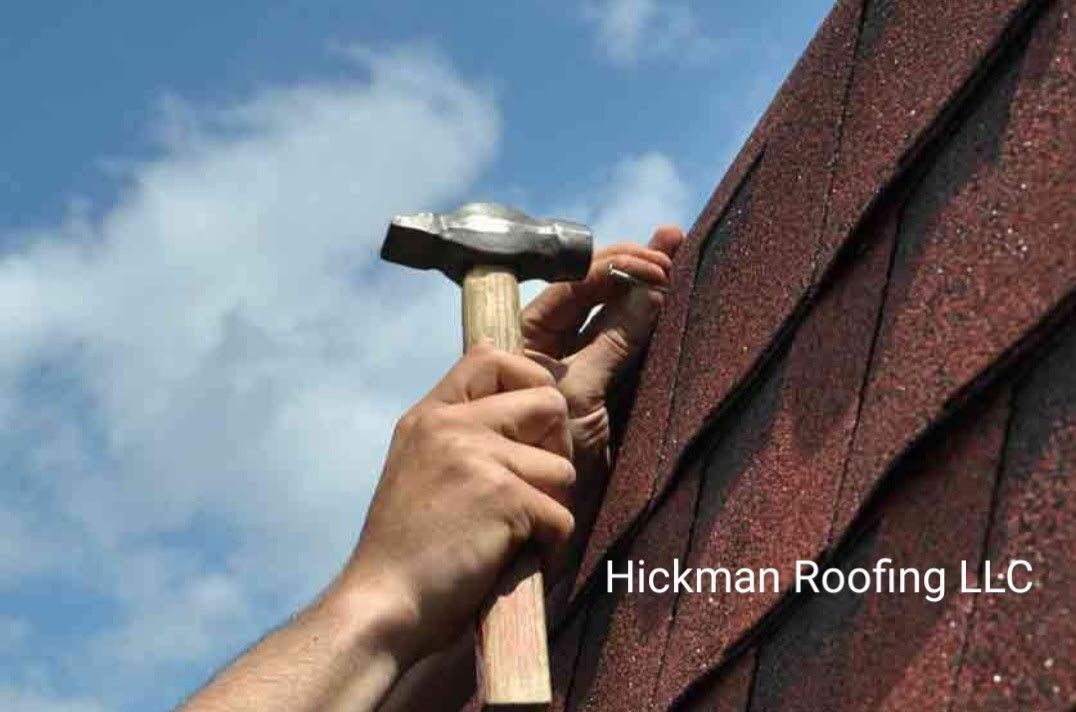A person is hammering a nail into a roof with a hammer.