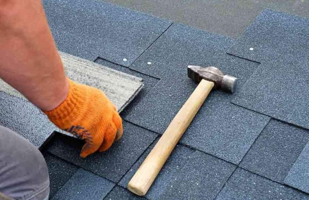 A person is working on a roof with a hammer.