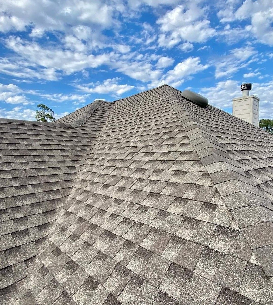A roof with a chimney on top of it and a blue sky in the background.