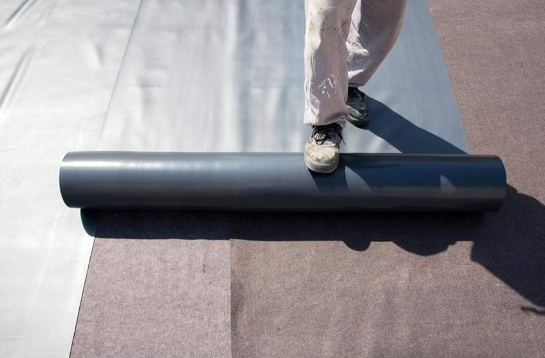 A person is standing on a roll of carpet.