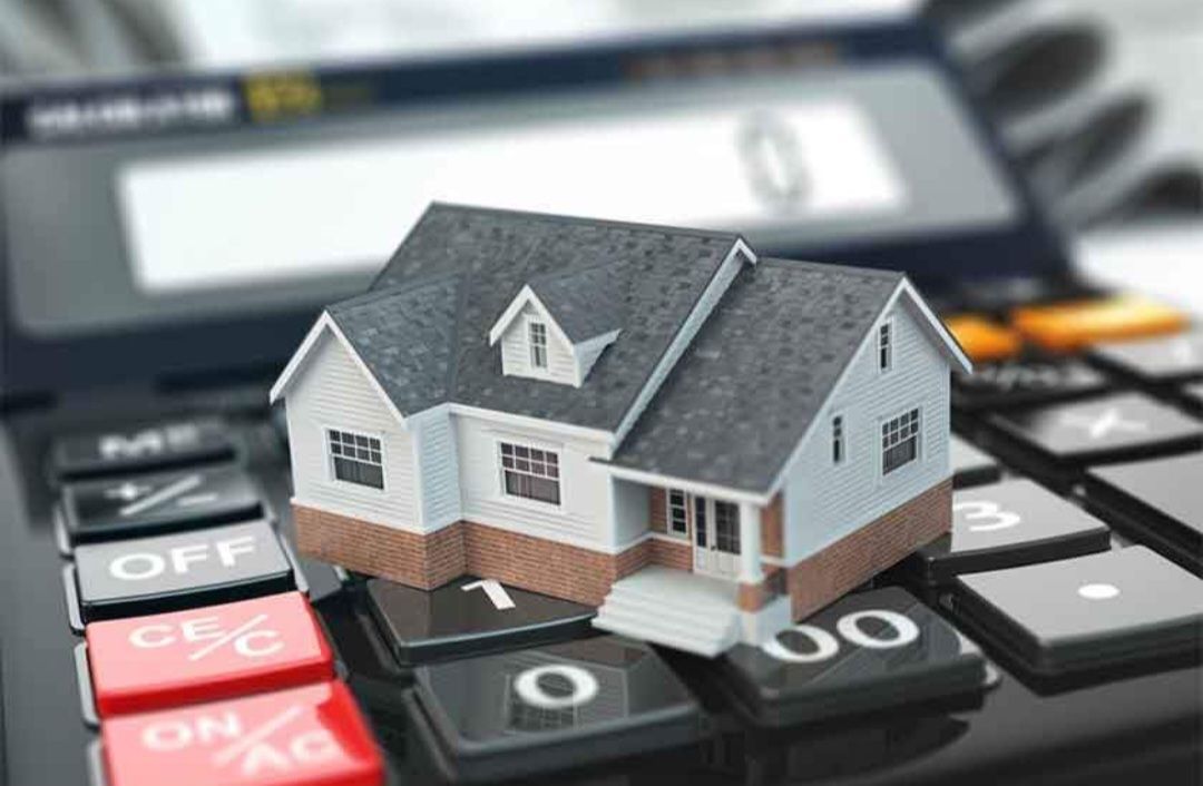 A model house is sitting on top of a calculator.