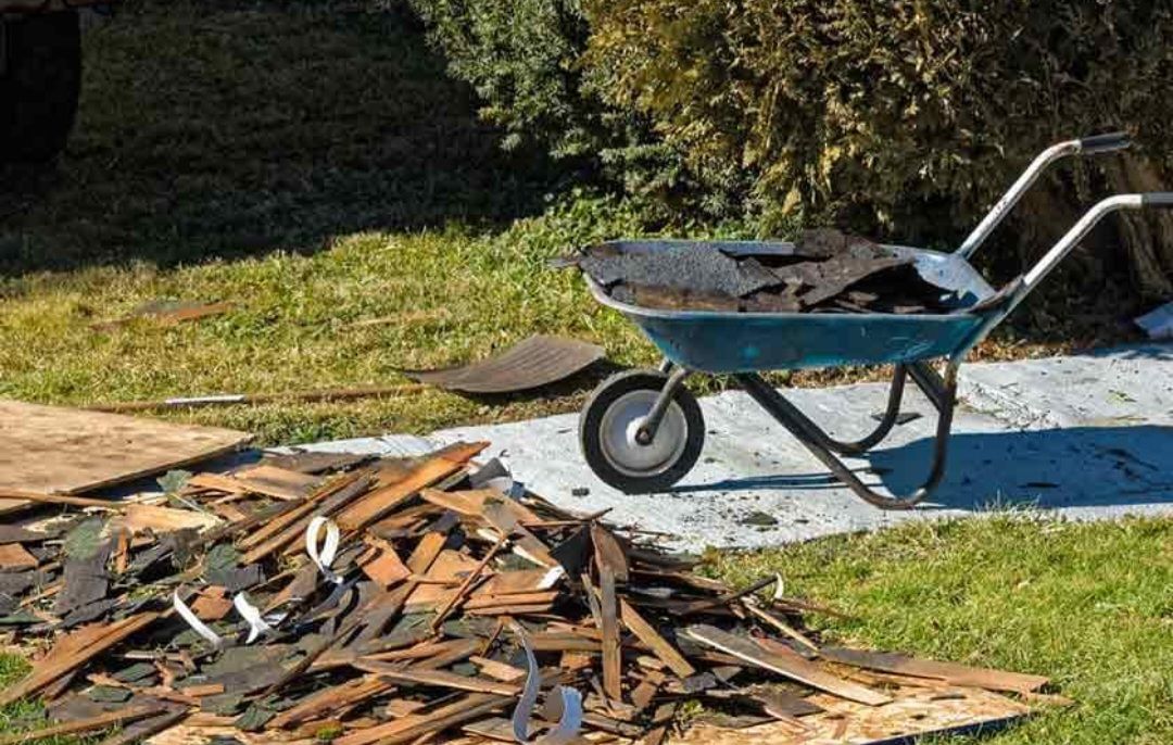 A wheelbarrow filled with wood chips is sitting on top of a pile of wood chips.