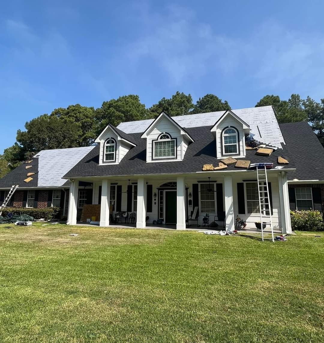 A large white house with a black roof is being painted.