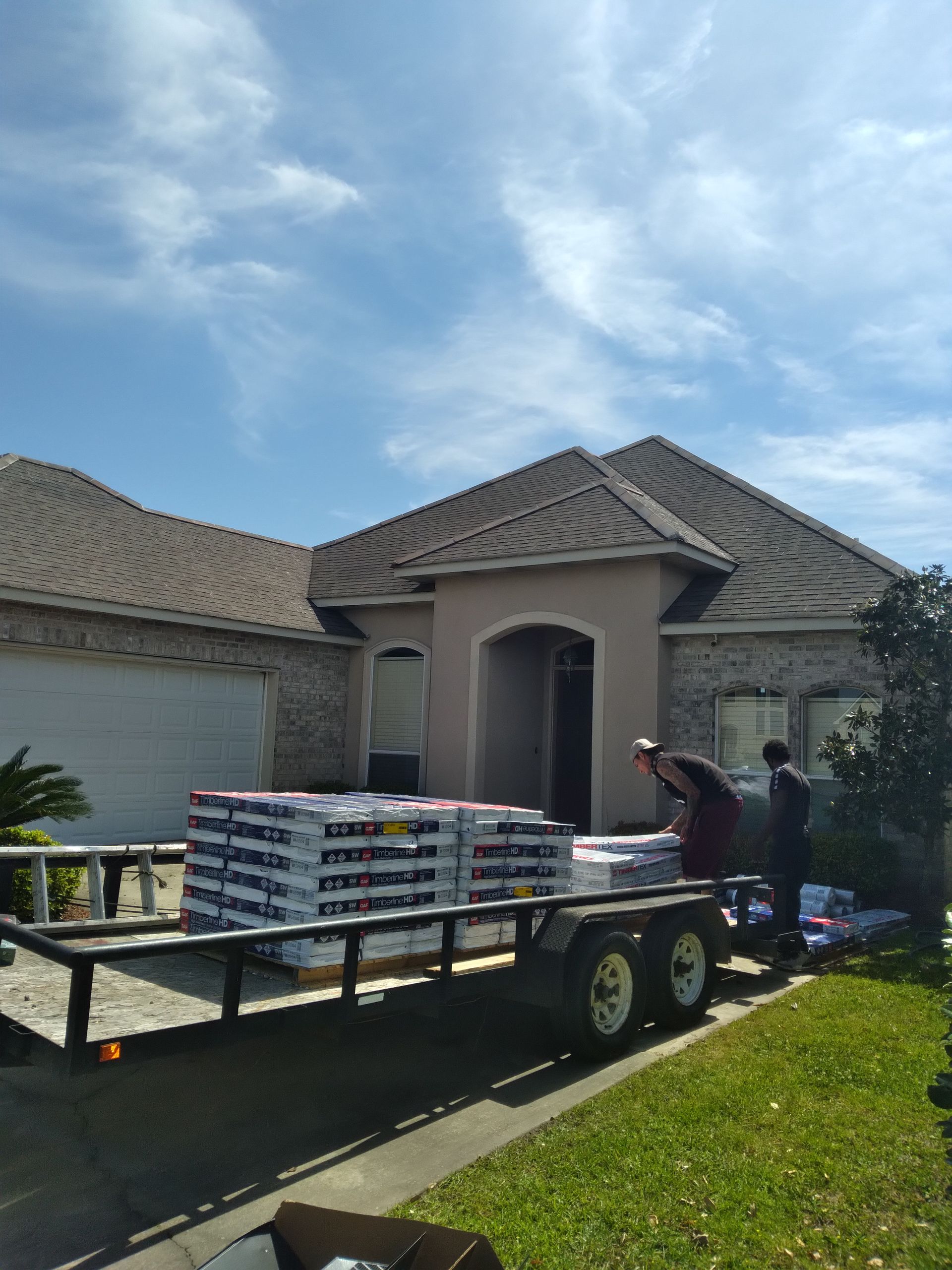 A trailer filled with bags of cement is parked in front of a house.