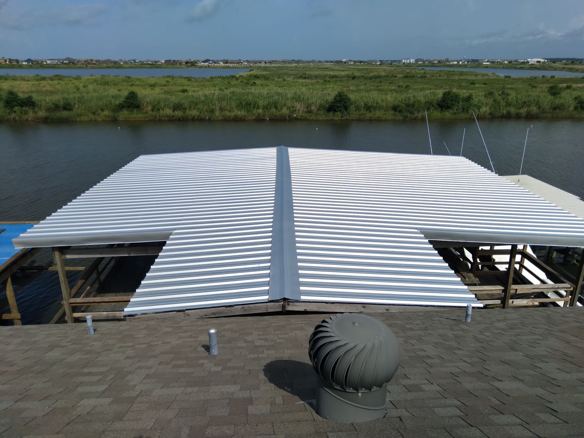 A roof with a wind turbine on it overlooking a body of water