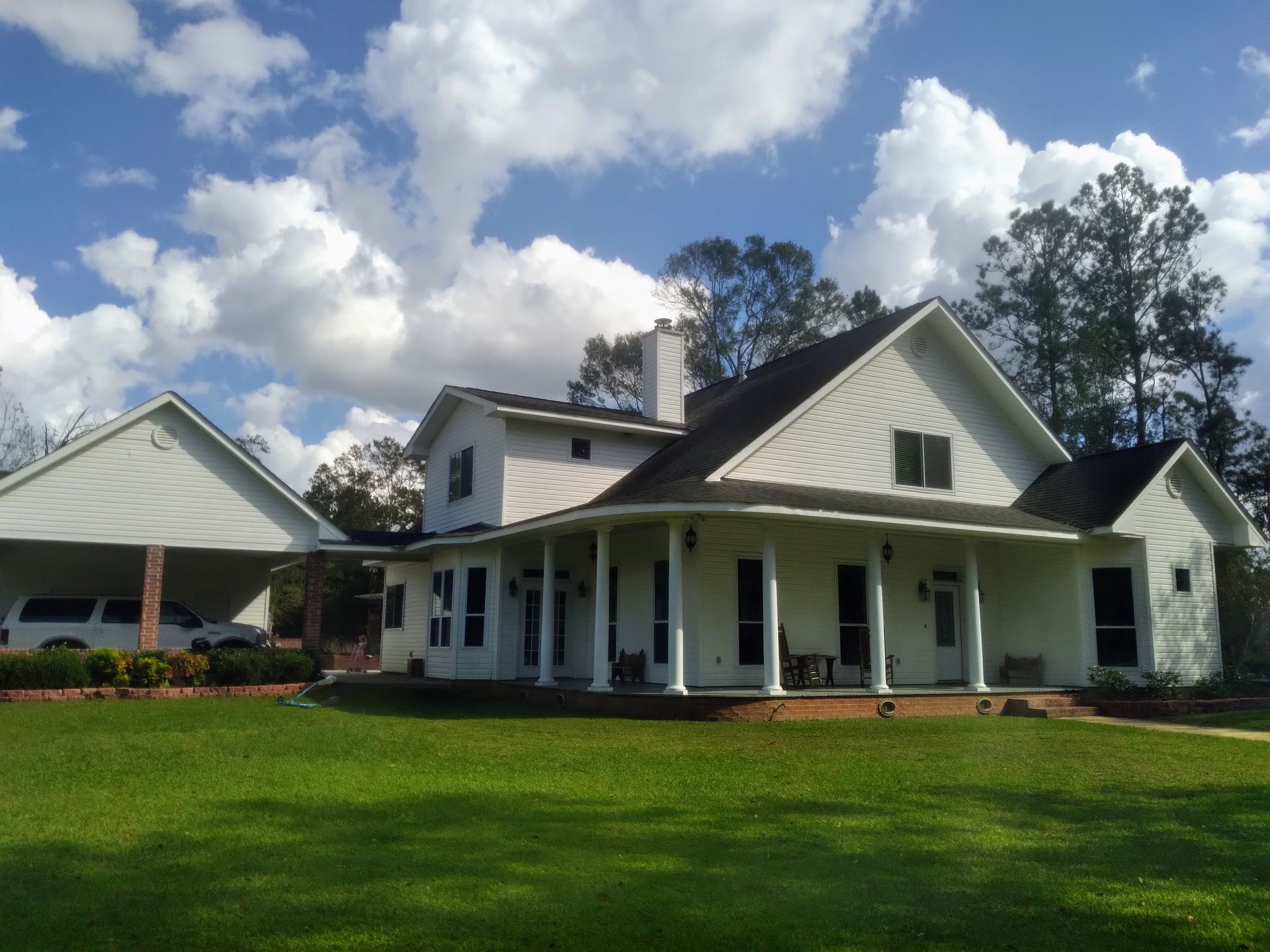A large white house with a porch and a carport