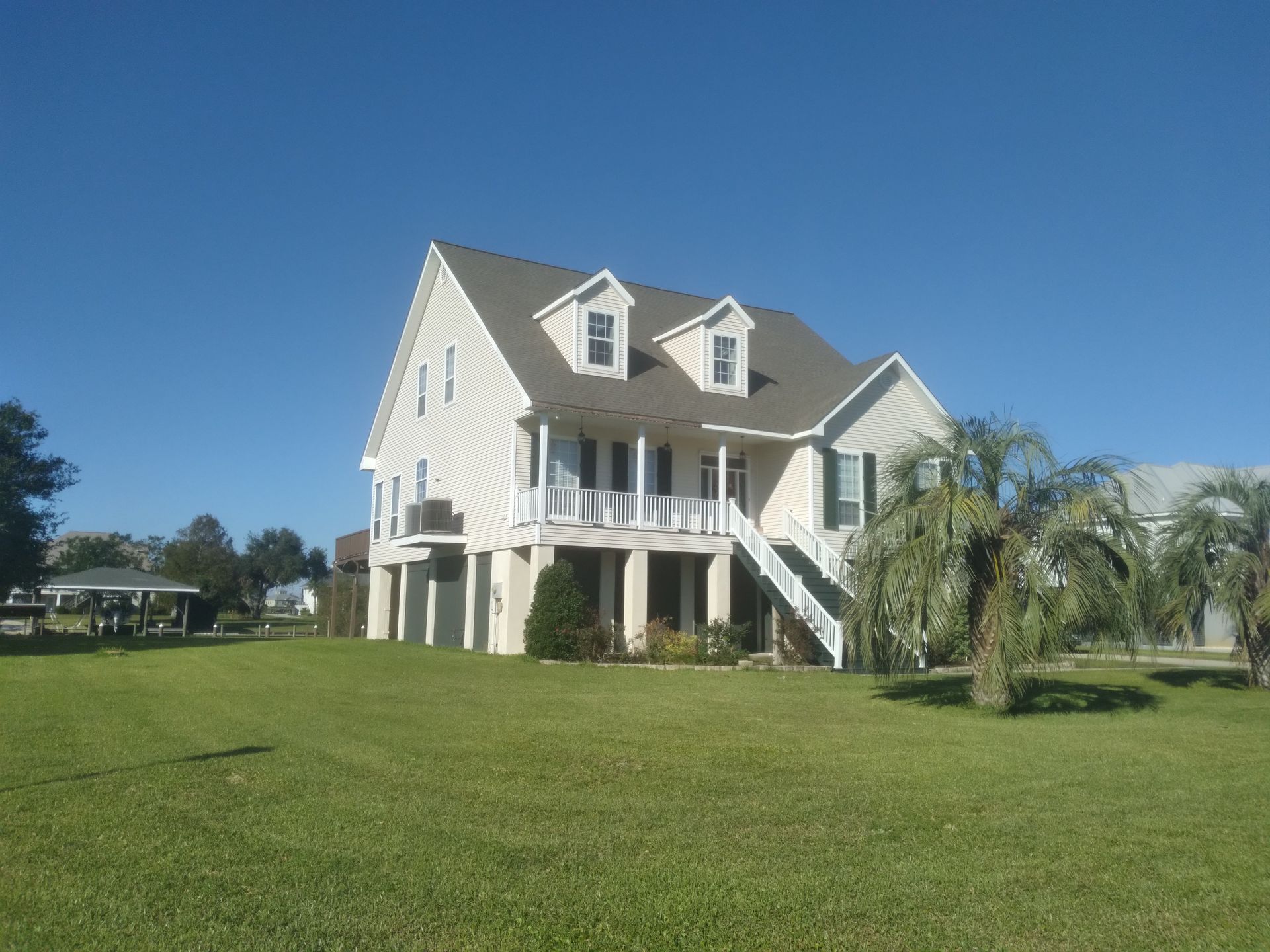 A large white house sits in the middle of a lush green field