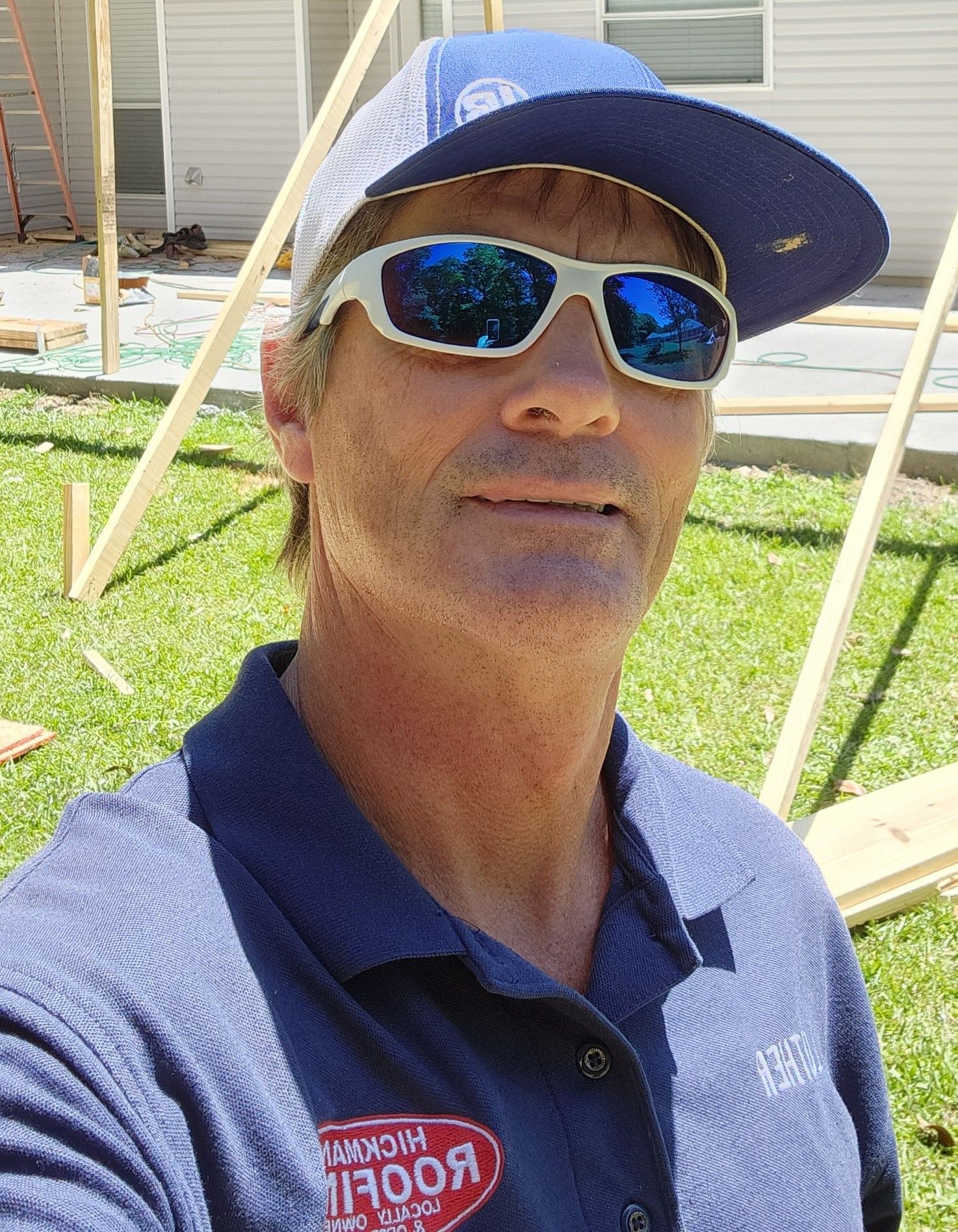 A man wearing sunglasses and a baseball cap is taking a selfie.