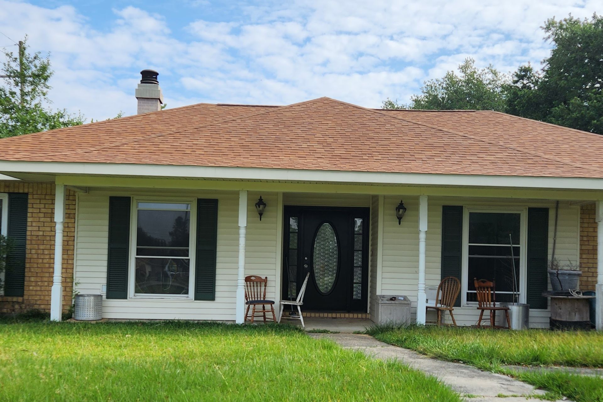 A white house with a brown roof and black shutters