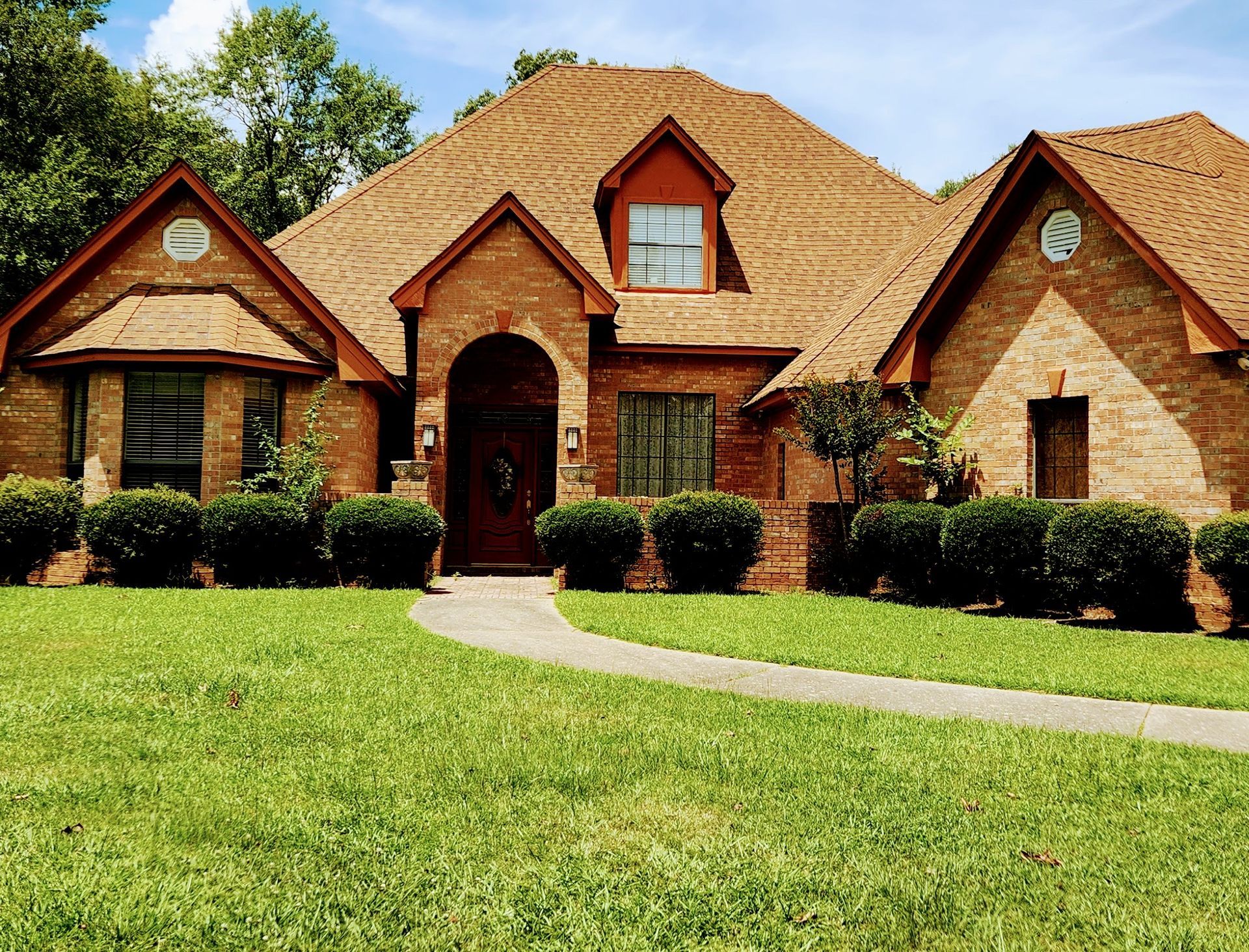 A large brick house with a lush green lawn in front of it