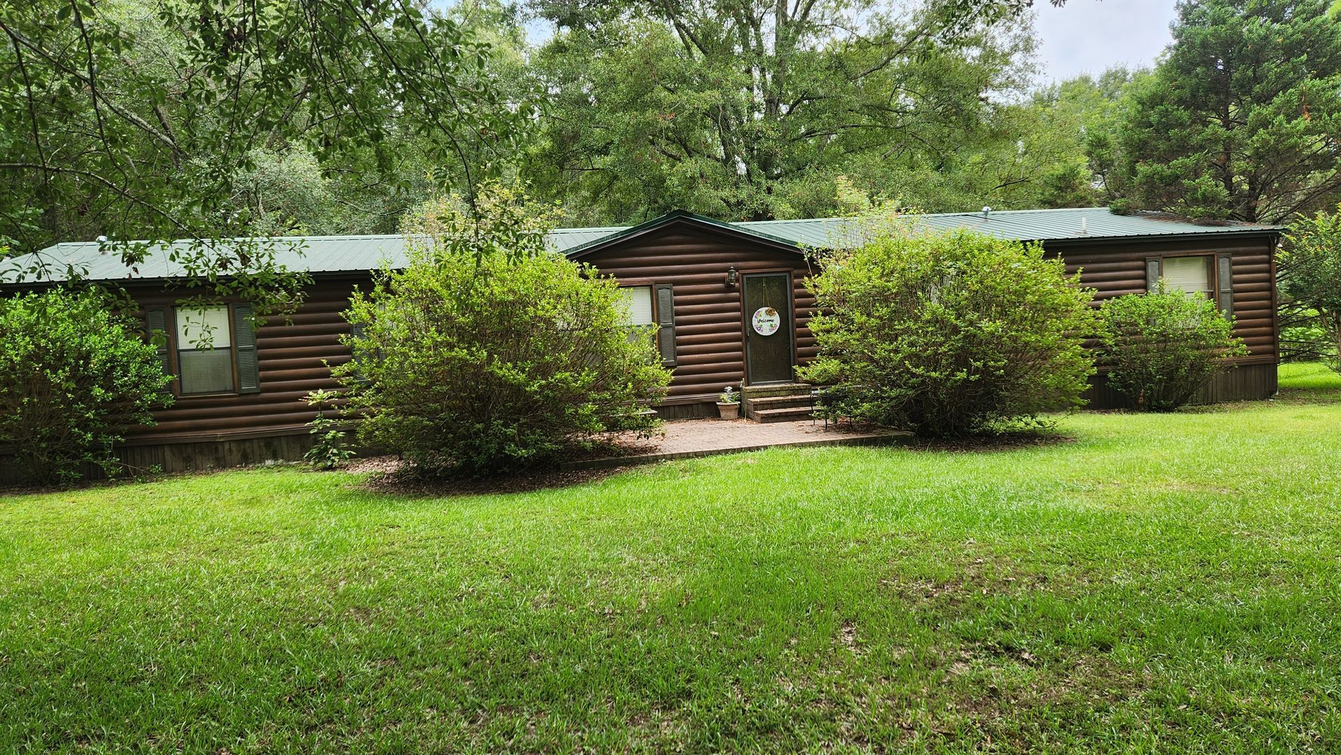 A log cabin is sitting in the middle of a lush green field.