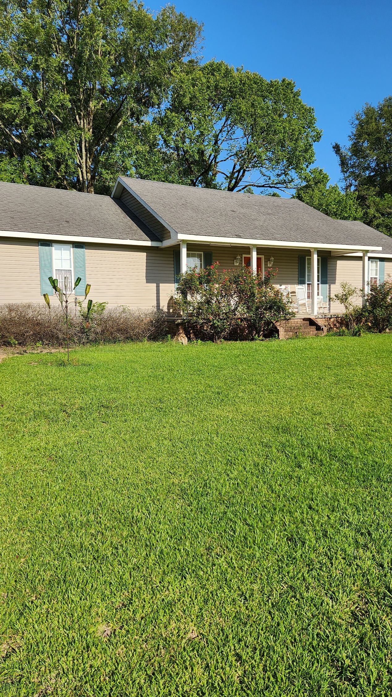 A house with a lush green lawn in front of it.