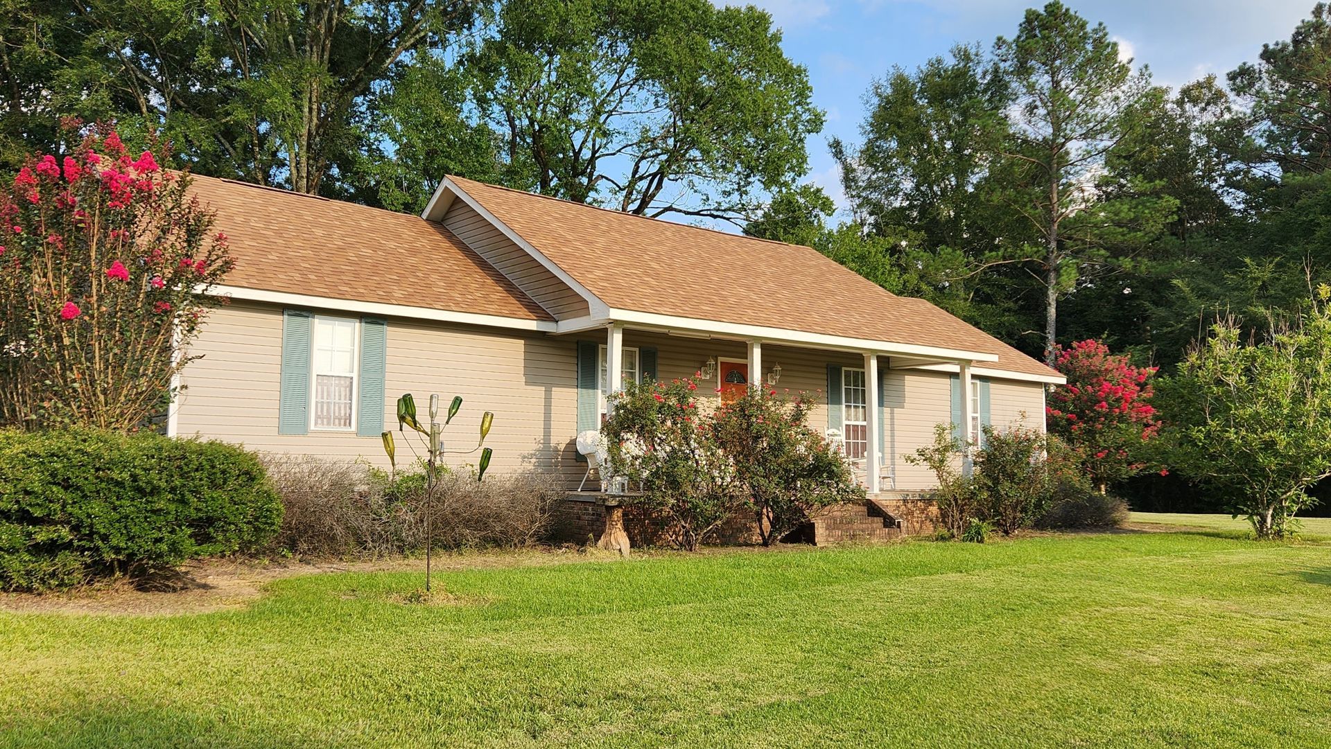 A house with a brown roof is sitting on top of a lush green field.