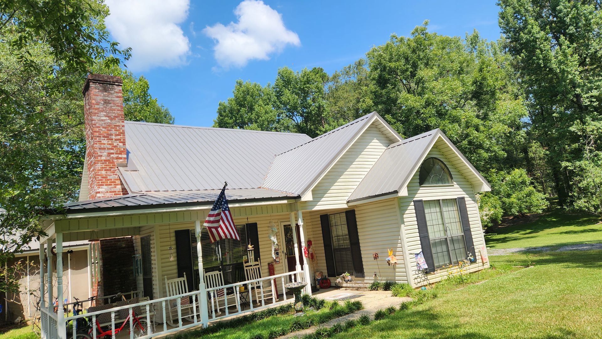 A white house with a porch and an american flag on it.