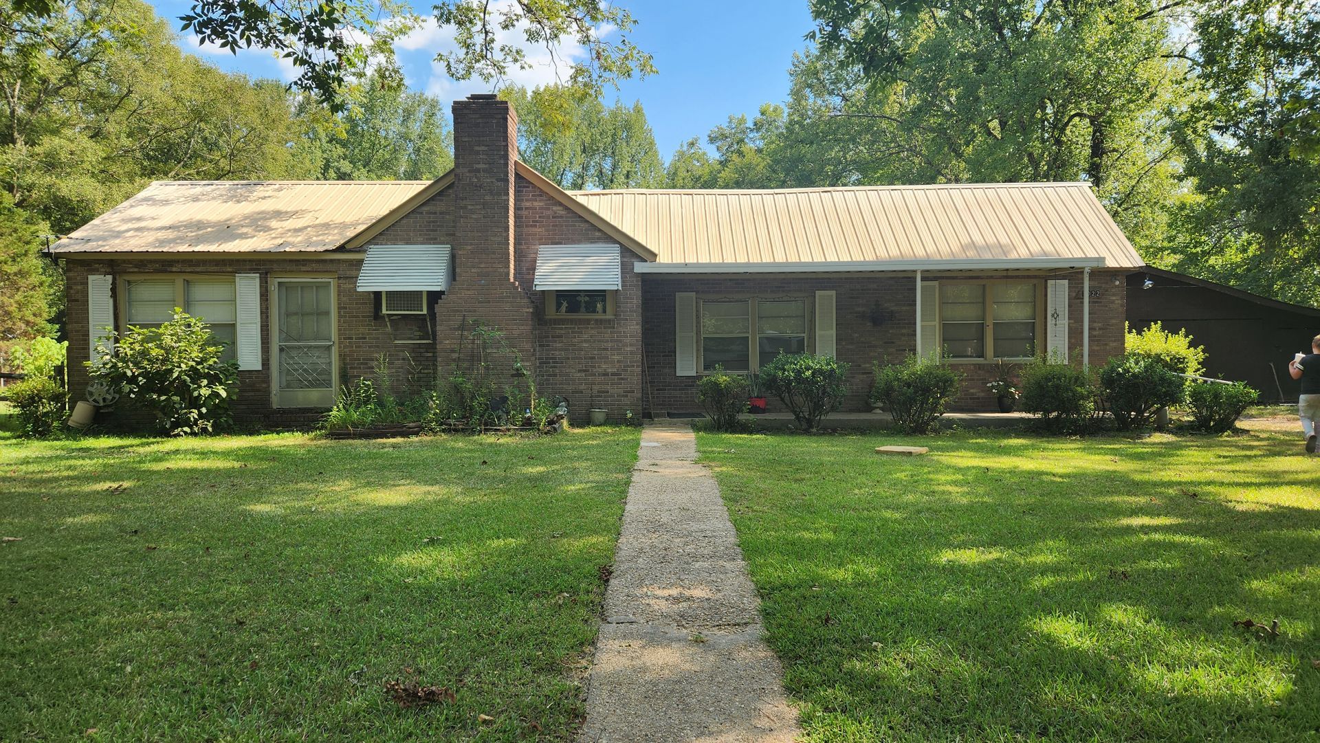 A brick house with a white roof and a walkway leading to it.