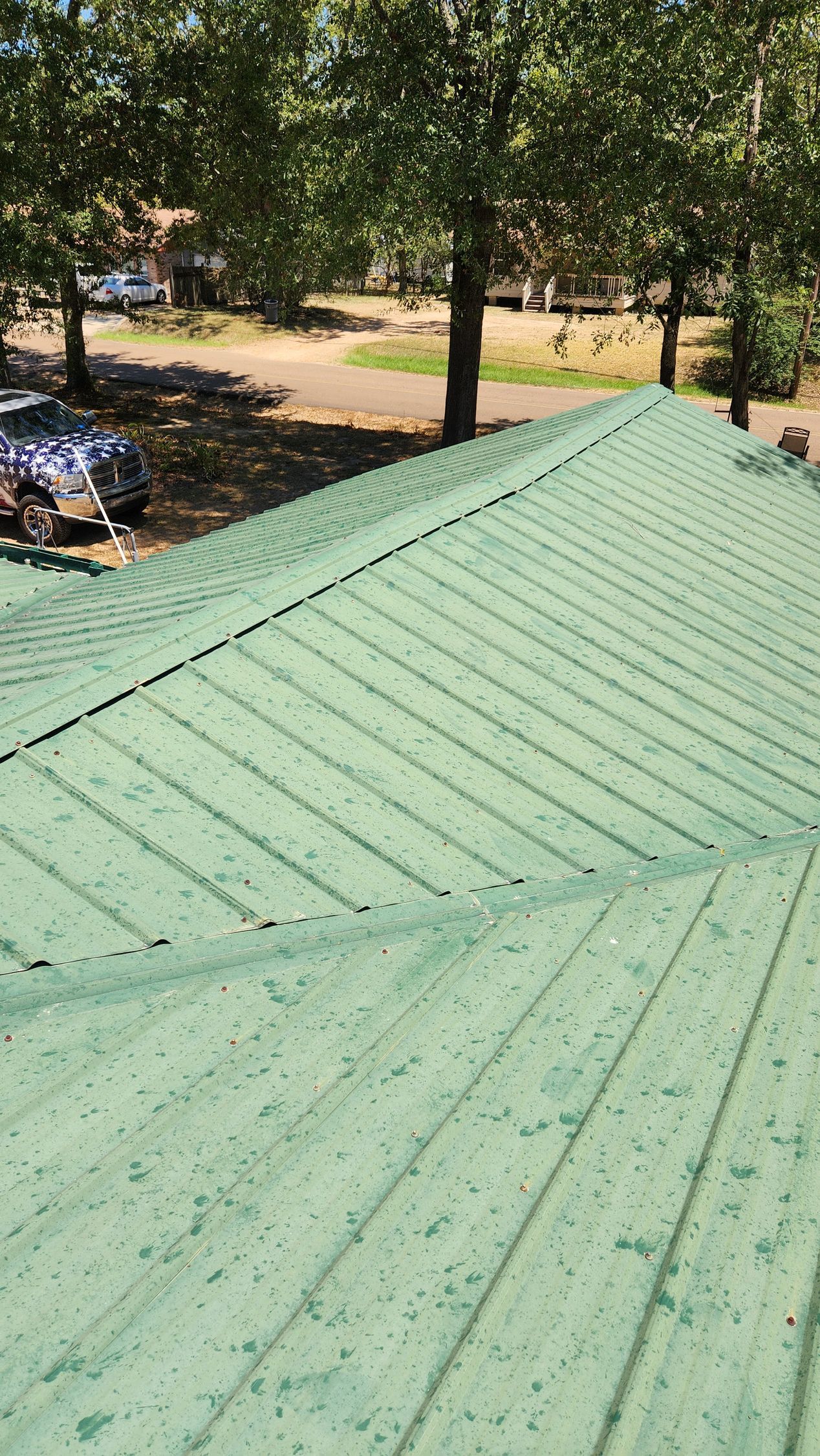 A green metal roof with trees in the background.