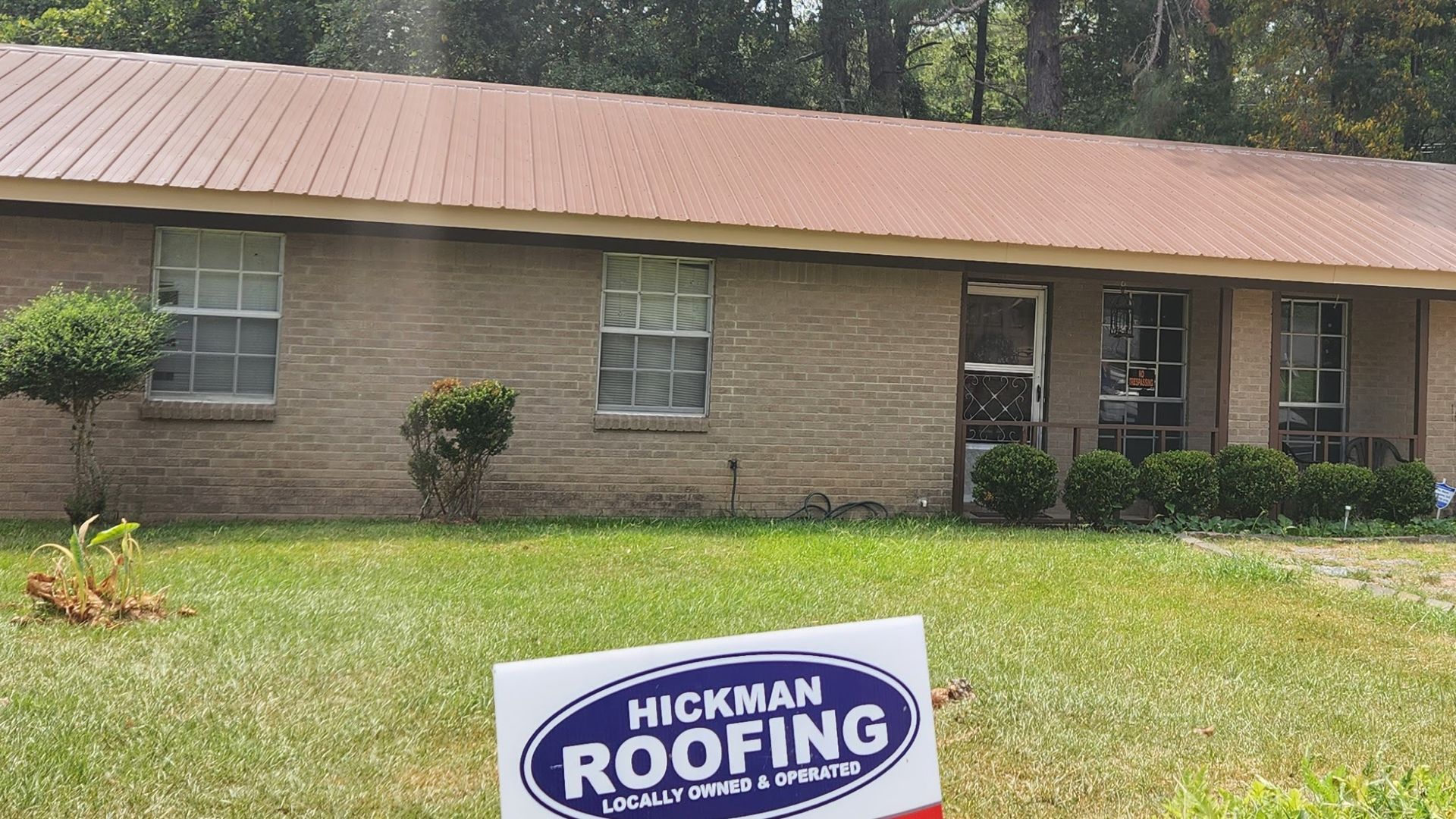 A house with a sign in front of it that says hickman roofing.