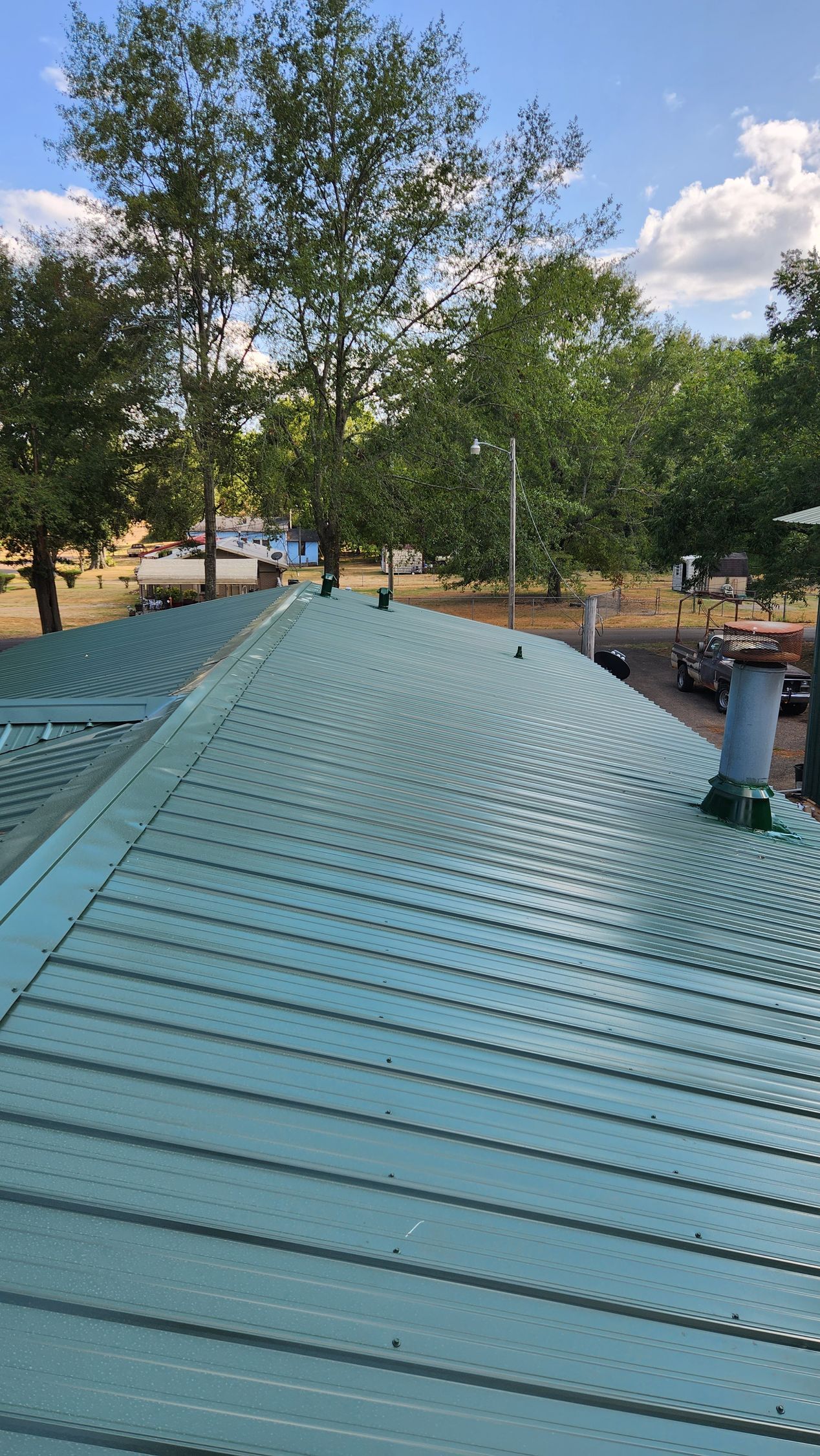 A green roof with trees in the background and a blue sky in the background.