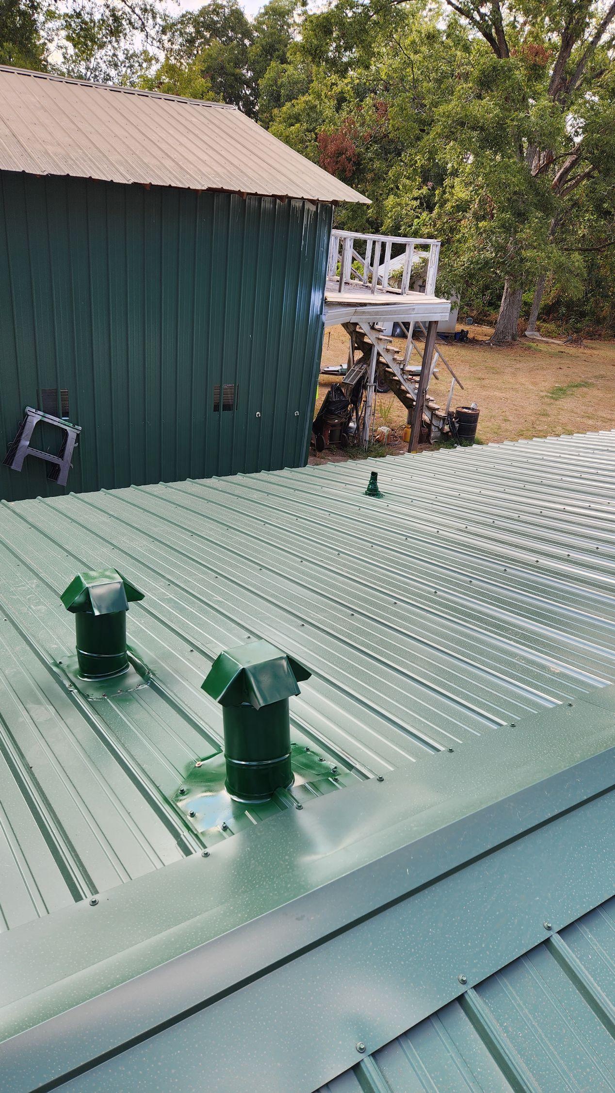 A green roof with two green chimneys on it.