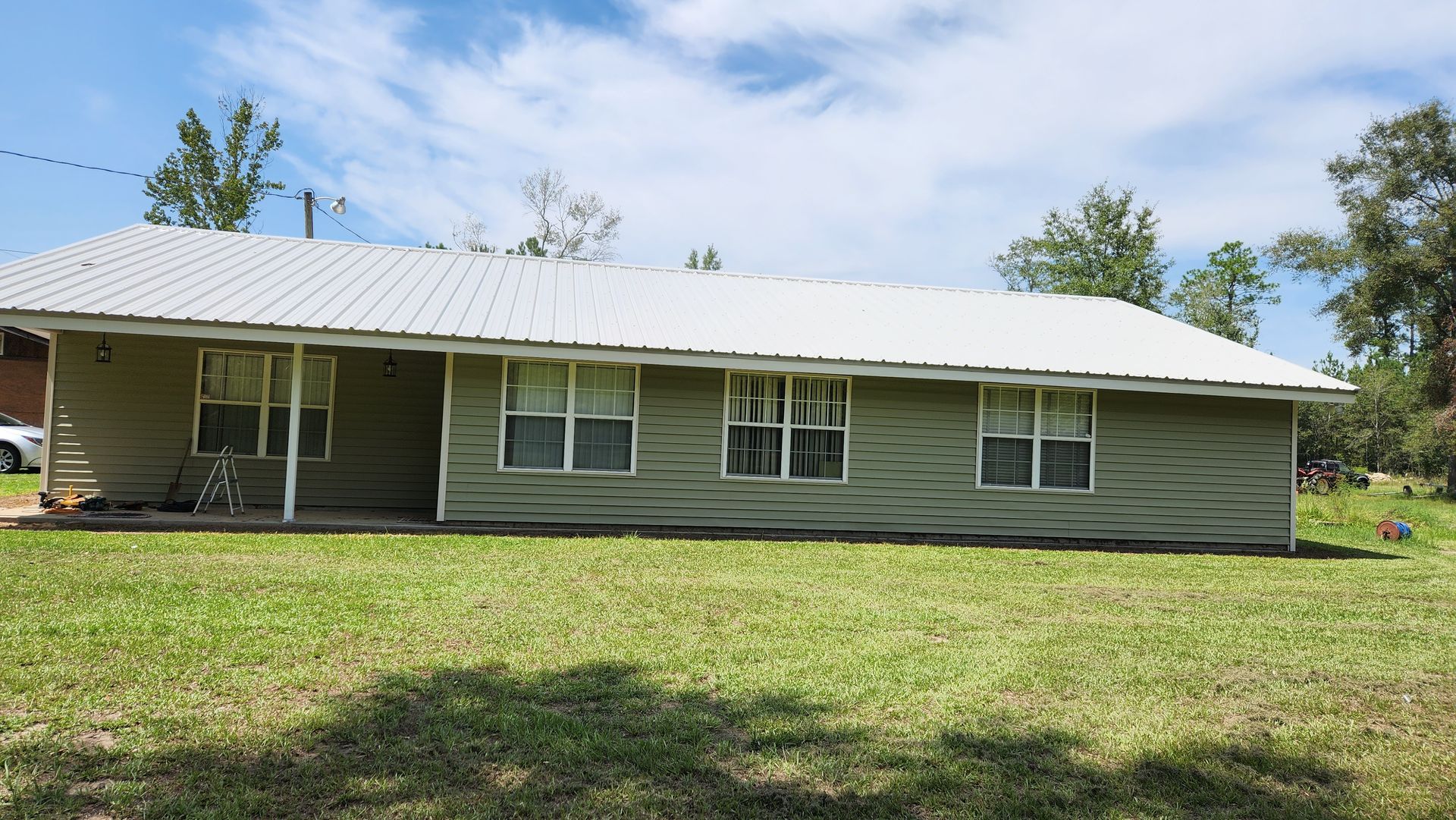 A house with a metal roof is sitting on top of a lush green field.