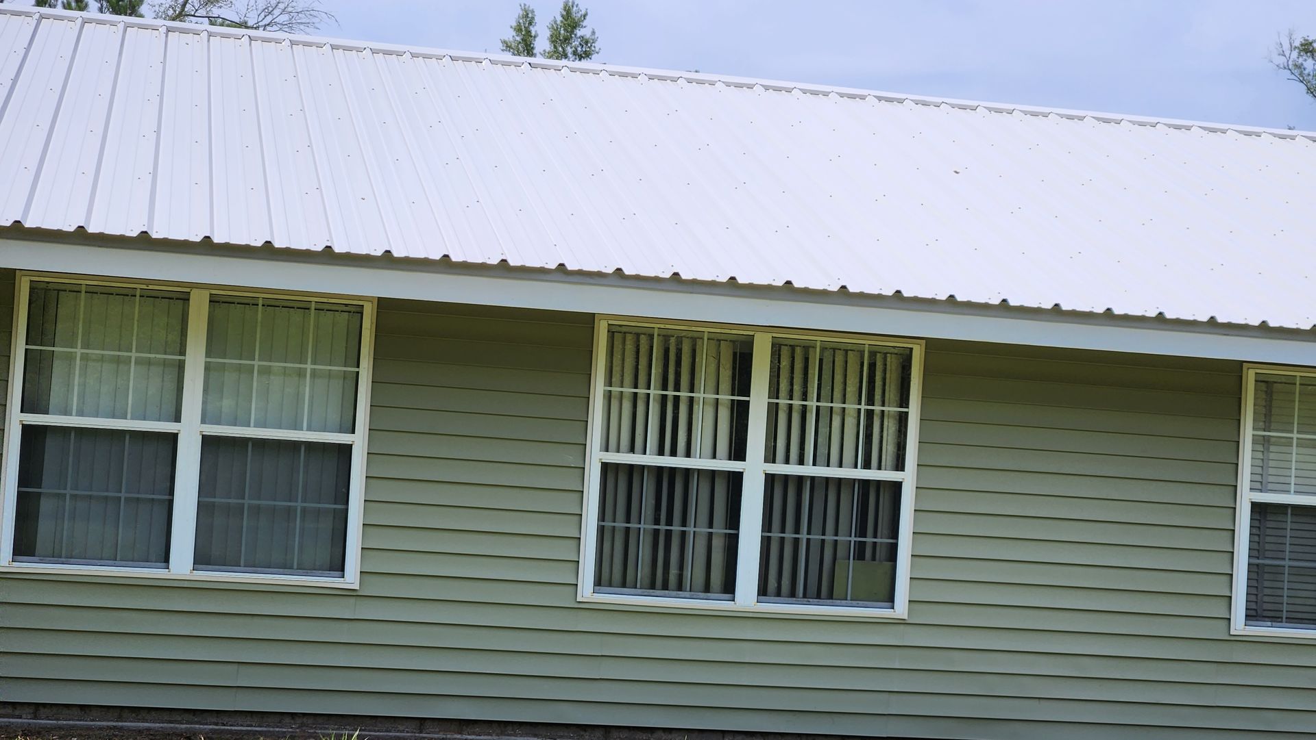 A green house with white windows and a white roof.