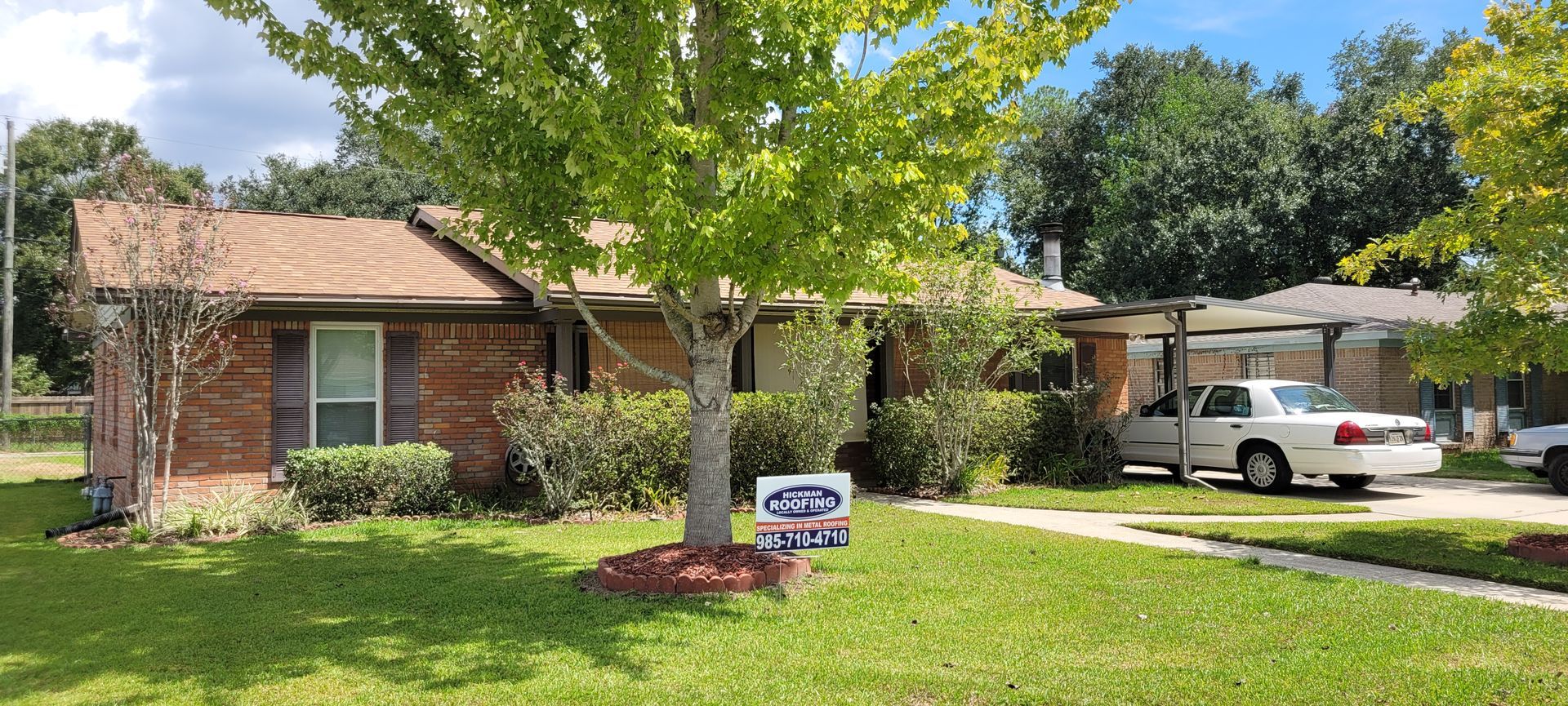A white truck is parked in front of a brick house.